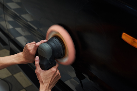 Hands with daul action polisher. polishing on car surface. foam pad in blur motion from vibration of polisher machineの写真素材