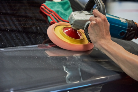 Hands Polishing Car With Rotary Car Polisher. Polishing On Car Paint Surface. Foam Pad In Blur Motion From Vibration Of Polisher Machine. Selected Focusの写真素材