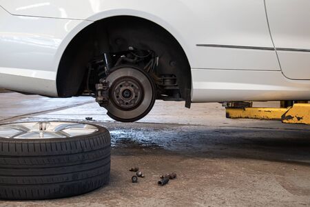 Car Lifted In Auto-Repair Service For Fixing And Tire Lay Down On Floor.の写真素材