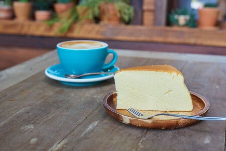 Piece Of Japanese Cheesecake In Wooden Plate And Blue Cup Coffee Blackground.の写真素材