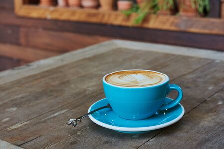Blue Cup Of Coffee With Latte Art On Wood Tableの写真素材