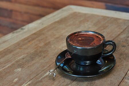 Hot Chocolate In Black Cup On Wooden Tableの写真素材