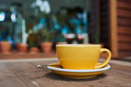 Yellow Cup Of Coffee With Latte Art On Wood Tableの写真素材