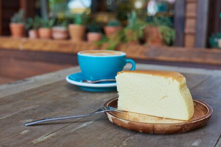Piece Of Japanese Cheesecake In Wooden Plate And Blue Cup Coffee Blackground.の写真素材