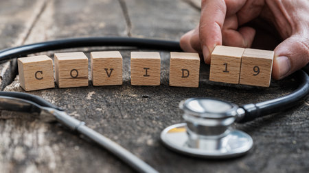 Covid 19 sign on wooden blocks next to a medical stethoscope.の写真素材