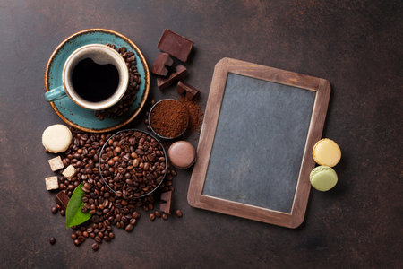 Coffee cup, beans and macaroons on stone background. Top view with blackboard for your textの写真素材