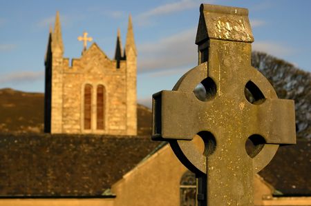 celtic cross with the church in the background in Irelandの写真素材