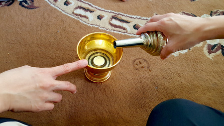 pouring ceremonial water into the containerの写真素材