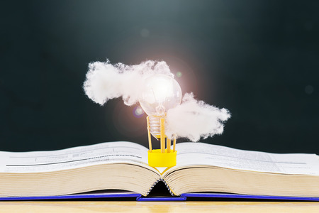 Balloon made from light bulb, floating on the book There are clouds floating, books placed on the...
