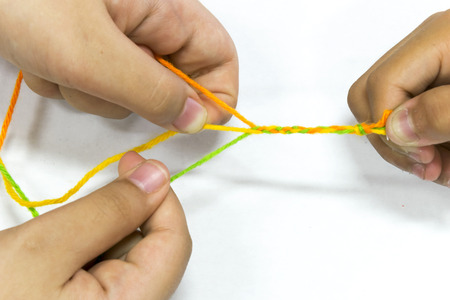 Knitting by hand, Use 3 lines of orange, yellow, green, knit together, Have 2 children working.の写真素材