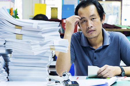 Employees who work hard with large documents, salary man stressful with a lot of work, The table is full of accessories disorganized, Is using ideasの写真素材