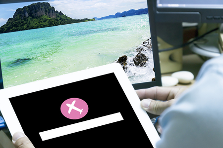 Smartphone home screen, flight icon in the focus,finger tip is about to launch application,on the background Black Sea searching for infomation travel plan - Trip vacation,tourism mockup - Outfit of traveler on wooden background.の写真素材