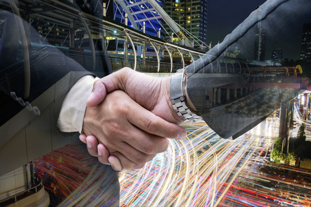 Close up of business people handshake on big city at night background,The abstract image of the businessman handshaking with another,The concept of agreement,partnership and successful.の写真素材