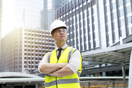 Construction manager of a large-scale project,requires a very high level of expertise,A strong will to succeed,Wear a shirt,tie a black,wear green safety vest and white safety helmet,In the big city.の写真素材