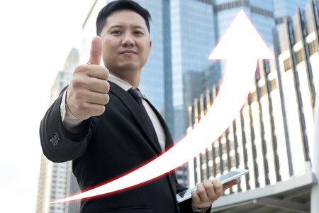Success concept with businessman wear black suit showing thumbs,Asian business catch the upward arrow,concept of growth,stock,marketing,Investment concept.の写真素材