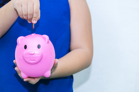 The girl in blue shirt,future saving concept,Cute asian little girl playing with coins making stacks of money,kid saving money for the future concept,hand putting money into piggy bank.の写真素材