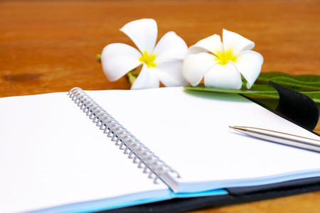Open book,pen and Plumeria in pot on wooden desk.Taking notes is a memorandum.Many important lessons learned from the recording.の写真素材