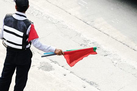 Security guard working on traffic to make it convenient,Hold a red and green flag for use as a signal.の写真素材