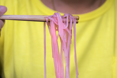 Street Food in Thailand,Woman wearing yellow shirt eating food,Use chopsticks to noodles,Popular Thai food.の写真素材