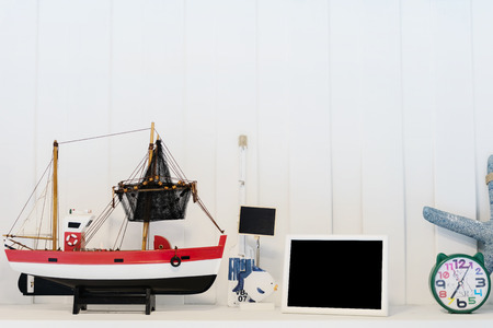 Traveling by sea is very popular, simulated fishing boats, photo frames, blackboard, starfish, placed on a white wooden backdrop.の写真素材
