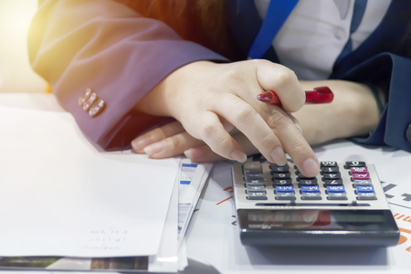 Business woman is calculating to pay, expenses. Use a calculator as a tool, and use a pen to take notes. It is a good business.の写真素材