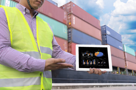 Officials show growth chart of investment on tablet. Transportation ship shipping is a popular method.The ship is waiting a lot of waiting.To make the country's economic growth.The work is ongoing.の写真素材
