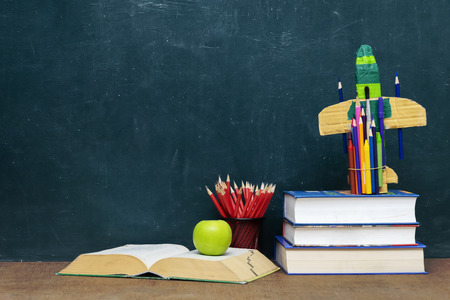 Success concept, Paper rocket made from pencils over chalkboard background, Books stacked and books open. Red pencil put Pencil holder and green apple.の写真素材