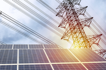 Electricity is a necessity for living. A large solar panel is the front. The backdrop is a high-power electric pole. The power distribution to the house. Solar Power Generation.の写真素材