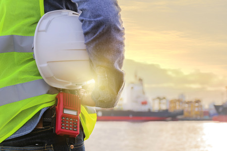 Engineers is listening to radio, Holding a white helmet. Working on the project. The backdrop is a huge industry. Professional work, Expertise and experience.の写真素材