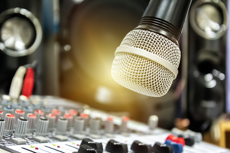 Sound technician control the music .Professional audio, mixer controller panel.Pro equipment for concerts.Stage lighting control.Hand adjusting audio mixer. The microphone is the focus.の写真素材