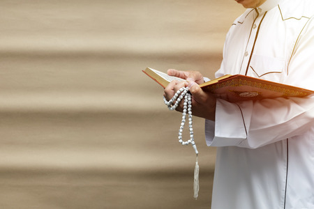 muslim man reading a book on color Brown gradient background, in Islam study. With intent and faith in religion.の写真素材