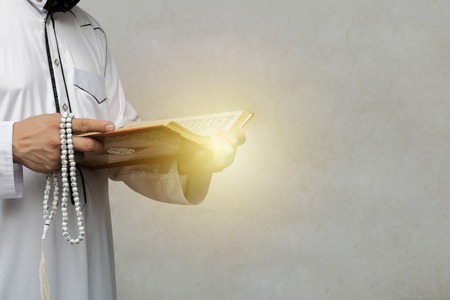 muslim man reading a Quran on gradient background, in Islam study. 
Have faith in religion. Beliefs and truths. There was a light of hope and faith.の写真素材