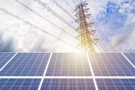 Electricity is a necessity for living. A large solar panel is the front. The backdrop is a high-power electric pole. The power distribution to the house. Solar Power Generation.の写真素材