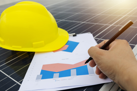 working solar station photovoltaic panels,solar energy,engineer working on checking and maintenance equipment at industry ,Chart Section Power consumption. Hold the pen to write.の写真素材