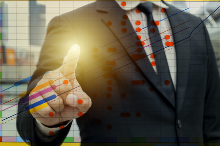 Business investment is profitable concept. Businessmen who are pointing to the growth curve of the business. Wear a black suit and shirt.の写真素材
