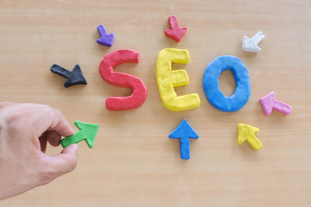 SEO, Search Engine Optimization ranking concept, Hand holding an arrow made of clay,pointing to alphabets abbreviation SEO at the center of wooden table, the idea of promote traffic to website.の写真素材