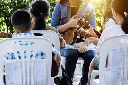 People sitting in class and practicing Ukulele play with tutor, mature teaching her student how to play Ukulele.のeditorial素材