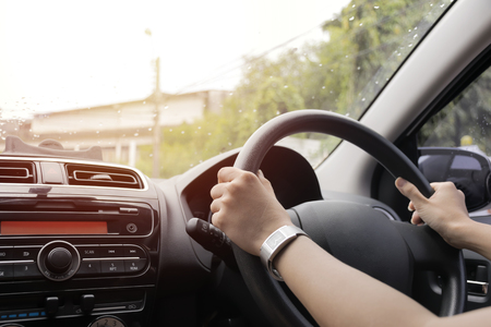 The girl was driving while the rain was falling. Need more security than usual. Use both hands to hold the steering wheel.の写真素材