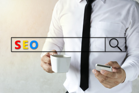 SEO, Search Engine Optimization concept. Businessman are using smartphones to find information and drinking coffee, Graphic Search and Magnifier.の写真素材