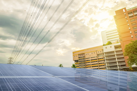 Renewable energy is very necessary in the future. Solar power is a popular source of electricity. 
The front of the property is a solar panel, the background is a large building with high-power poles.のeditorial素材