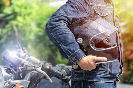 Handsome man in jean is standing near vintage motorcycle, And holding a helmet. To prepare to go to the destination.の写真素材