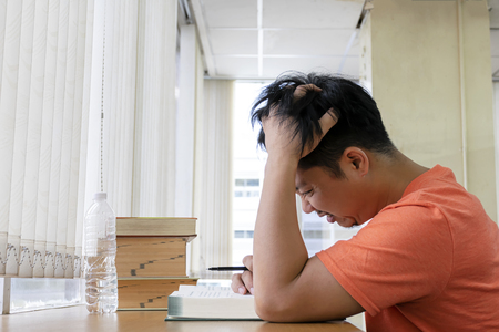 Guys are stressed with studying. Read books in the library, and use the ideas to review the content. Concerned about what will happen. Handles on the head and hair tangle.の写真素材