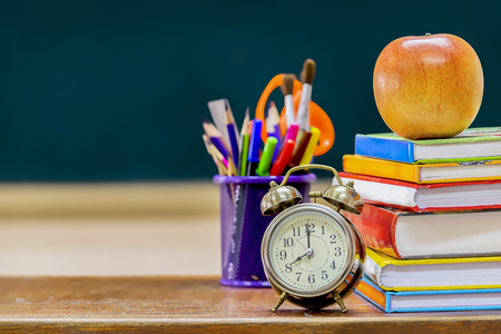 Back to school concept. Education is important for everyone, because it helps to succeed. To stimulate teaching, Front side the book is stacked and has a pencil case,Alarm Clock and red Apple.の写真素材