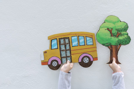 back to school concept. The children are holding a yellow school bus, tree. The wall is white. Education will improve your life. Great success must start with learning.の写真素材