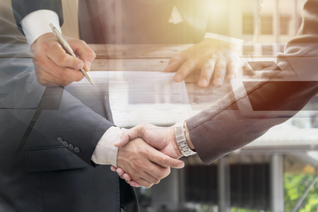 Business man signing contract making a deal and Shake hands to invest, classic business.Business contract. agreement was signed co-investment business. Investment data sheets are placed on the table.の写真素材