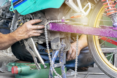 Motorcycle engine repair workers are working hard. To solve complicated mechanical engineering problems. The hand that smells oil.の写真素材