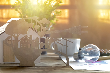 Paper cut of eco on desk. Home model, lamp, pen, document Stories about energy saving, happy families using clean electrical energy.の写真素材