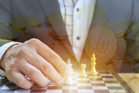 Businessmen who are playing chess by force the player to the other side. To fight the business that requires thought and strategy and planning. The background is gold.の写真素材