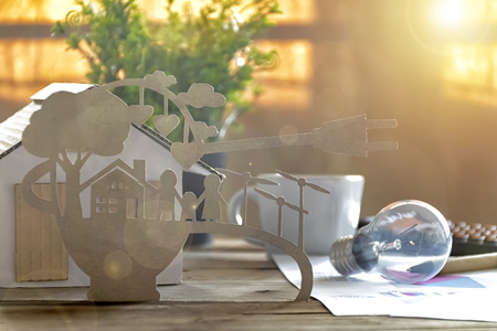 Paper cut of eco on desk. Home model, lamp, pen, document Stories about energy saving, happy families using clean electrical energy.の写真素材