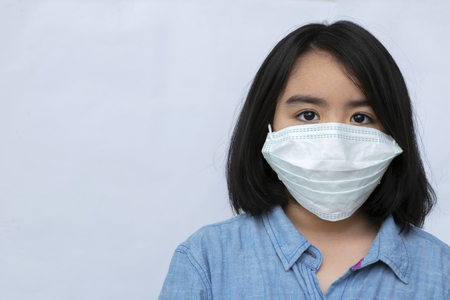 Studio portrait of unhealthy cute black Girl in white top with Health Mask, looks to the source of the allergy, place for advertising/Rhinitis, cold, allergy concept/の写真素材